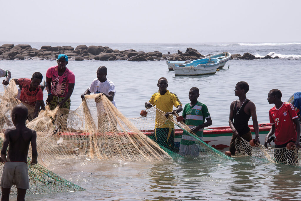 Dakar, Sénégal, pêcheurs et enfants remontant des filets de pêche sur la plage de Ngor au nord de la ville.